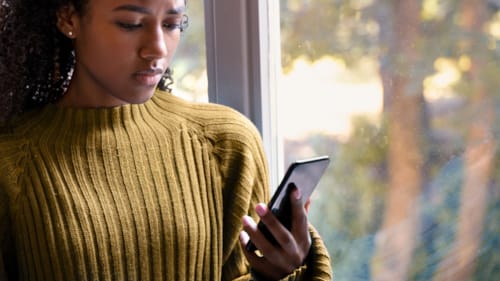 Kvinne som ser ned på mobilen sin