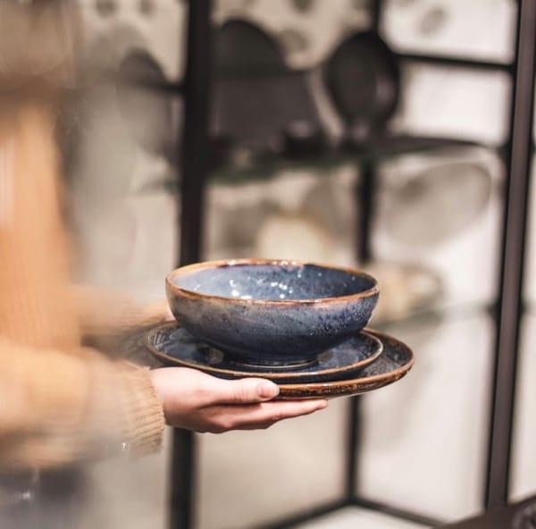 En person som holder et serveringsfat med en keramikkbolle på