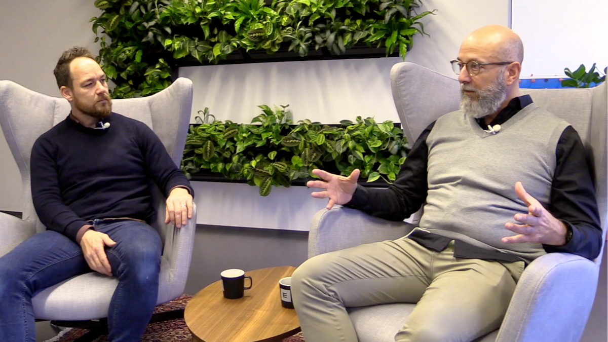 Arild Henrichsen og Geir S. Nodland sitter og snakker sammen i Epinovas lokaler. Mellom seg har de et lite bord med to kaffekopper på.
