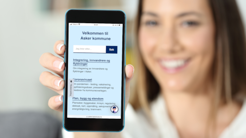 En dame holder frem en mobiltelefon med nettsiden til Asker kommune til kamera.