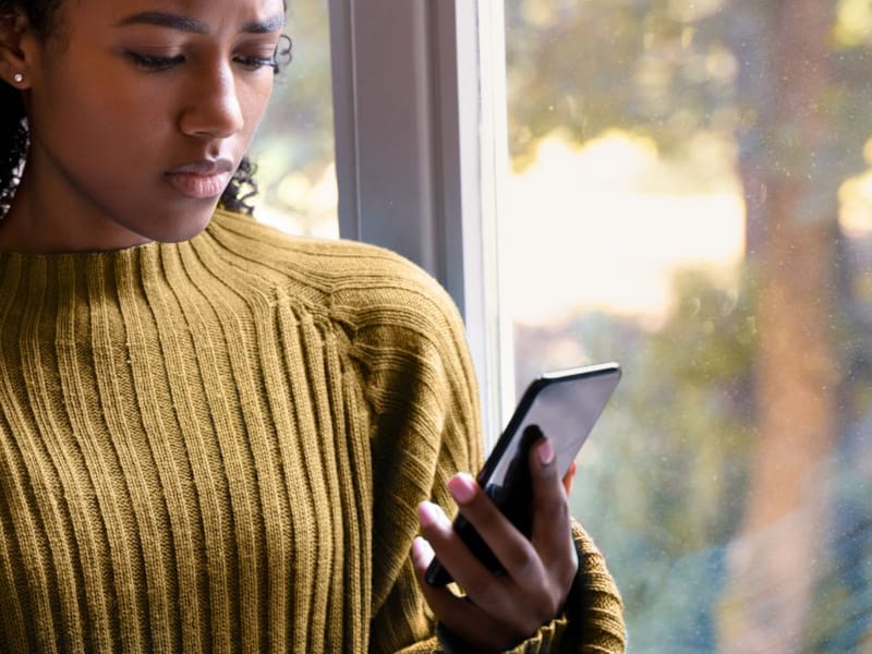 Kvinne ser ned på mobilen sin